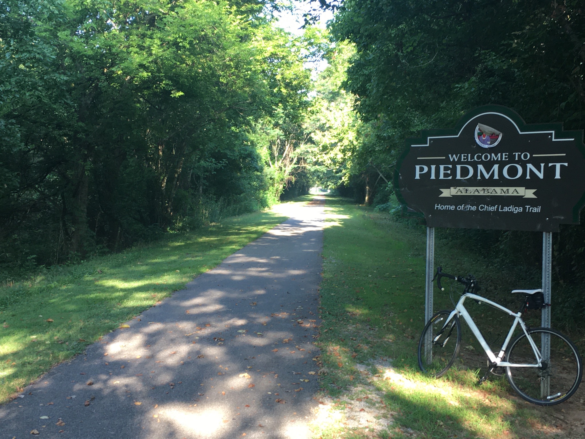 Welcome to Piedmont sign along the Chief Ladiga Trail with a bicycle.